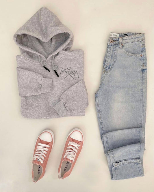 Gray hoodie, light blue jeans, and pink sneakers on a beige background