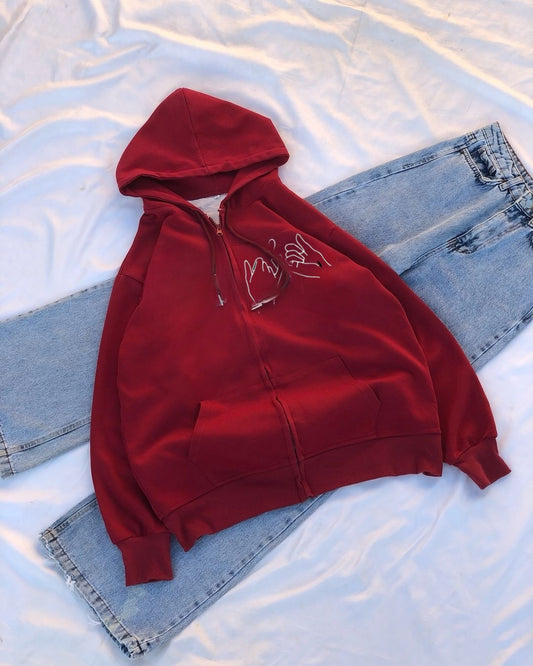 Red hoodie with a white logo on a light blue fabric background