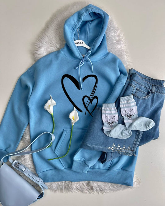 Blue hoodie with heart design, jeans, socks, and a bag on a textured surface